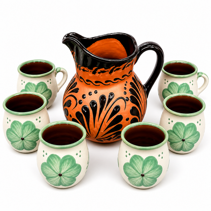 Ceramic pitcher and cups with green leaf patterns on a white background