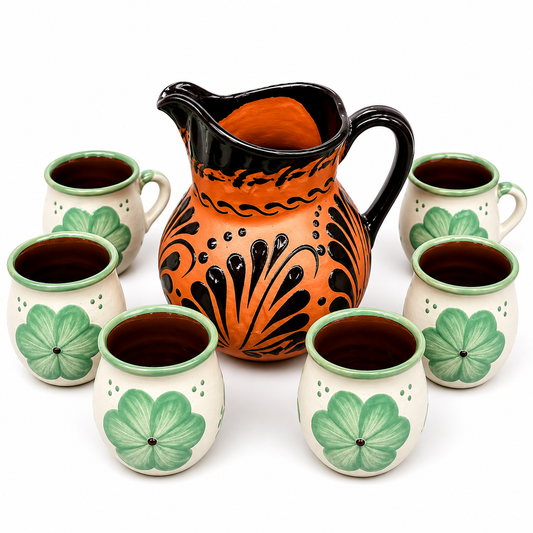 Ceramic pitcher and cups with green leaf patterns on a white background