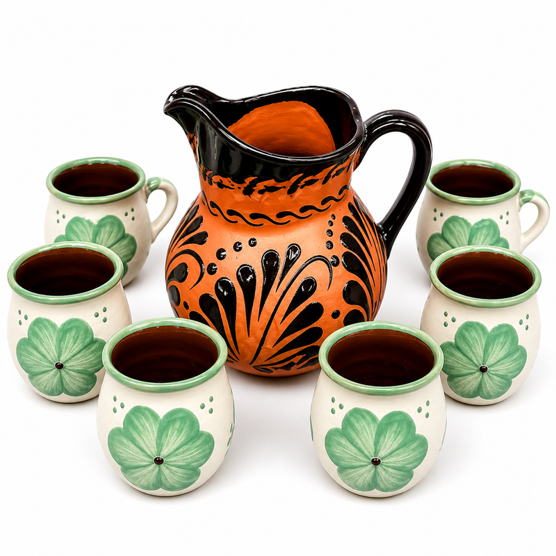 Ceramic pitcher and cups with green leaf patterns on a white background